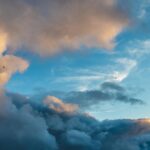 Dramatic sky with contrasting storm clouds and clear blue patches at sunset, symbolizing climate uncertainty and atmospheric change.