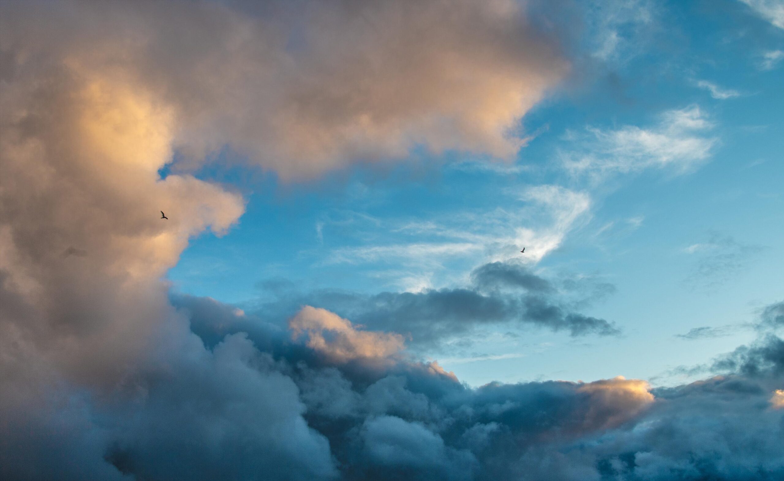 Dramatic sky with contrasting storm clouds and clear blue patches at sunset, symbolizing climate uncertainty and atmospheric change.